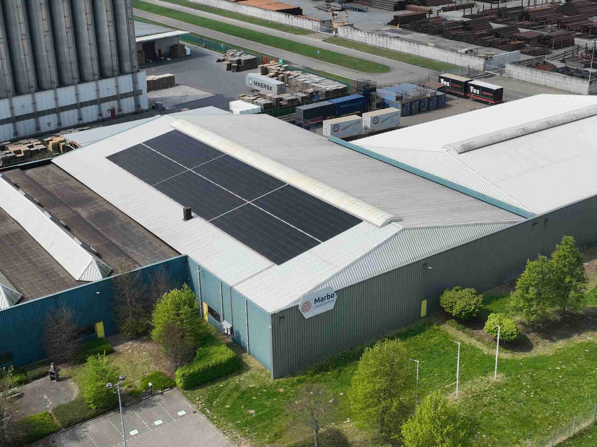 Een luchtfoto van een groot gebouw met zonnepanelen op het dak.