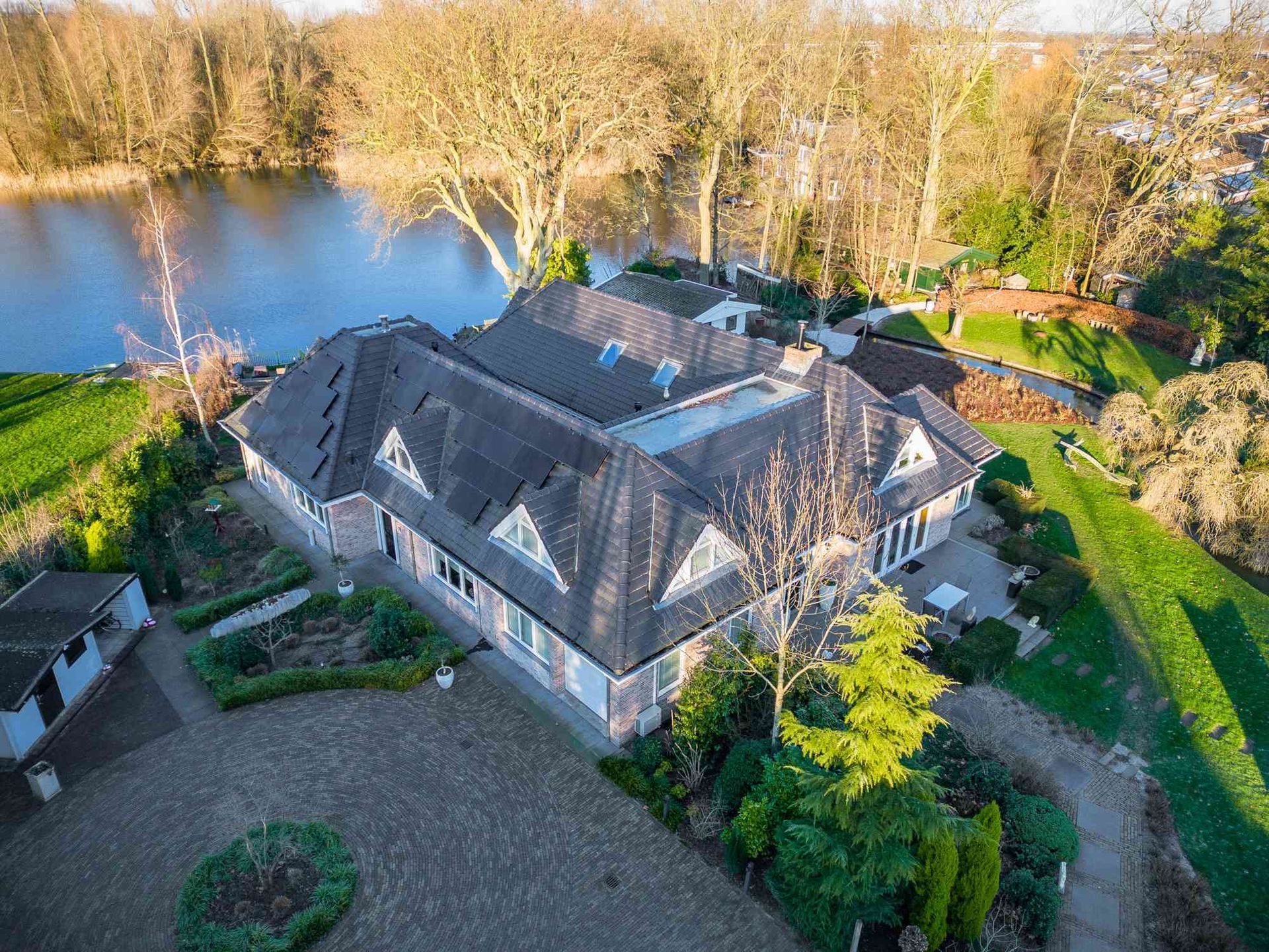 Een luchtfoto van een groot huis met een meer op de achtergrond.