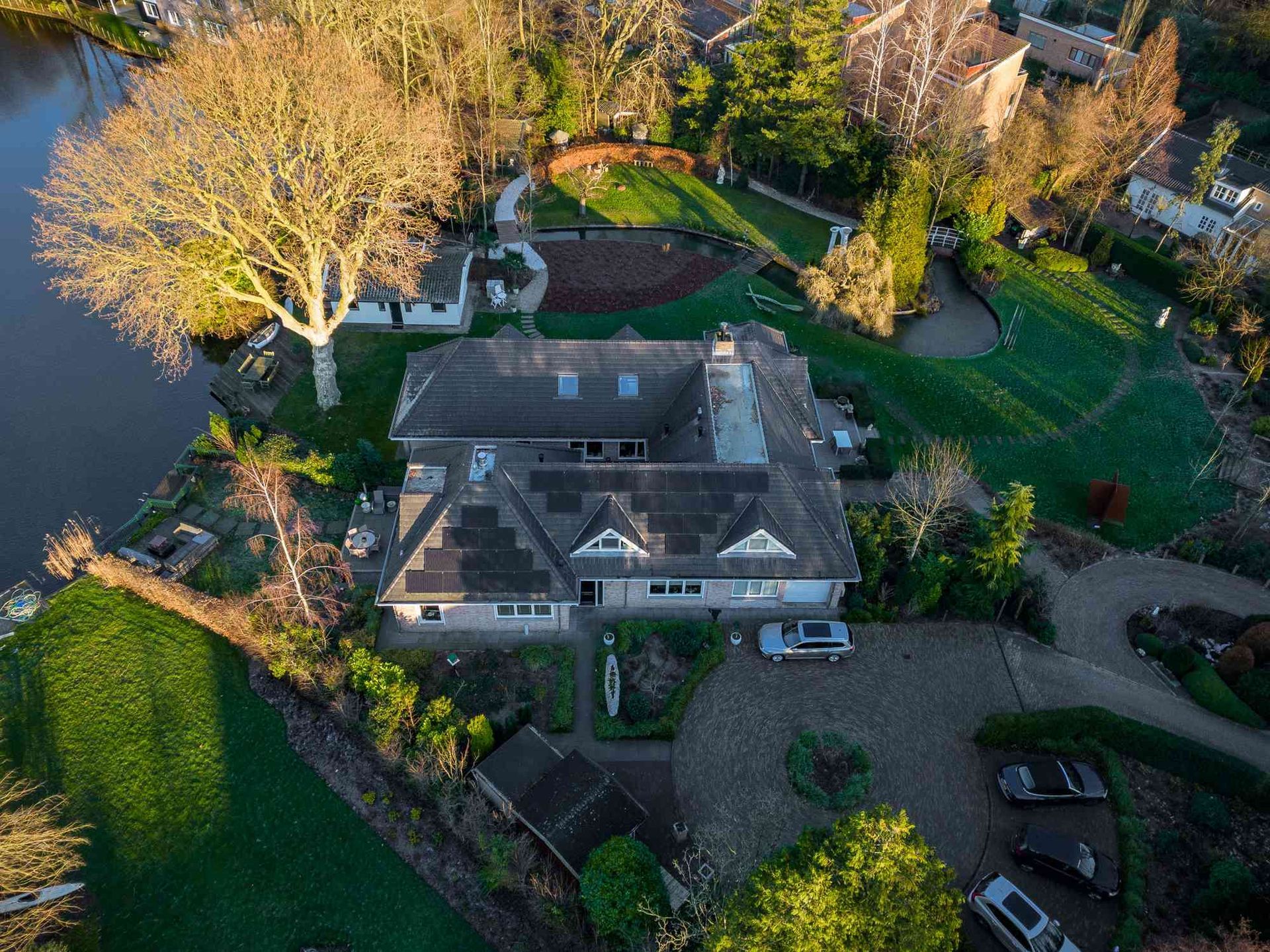 Een luchtfoto van een groot huis omgeven door bomen en een meer