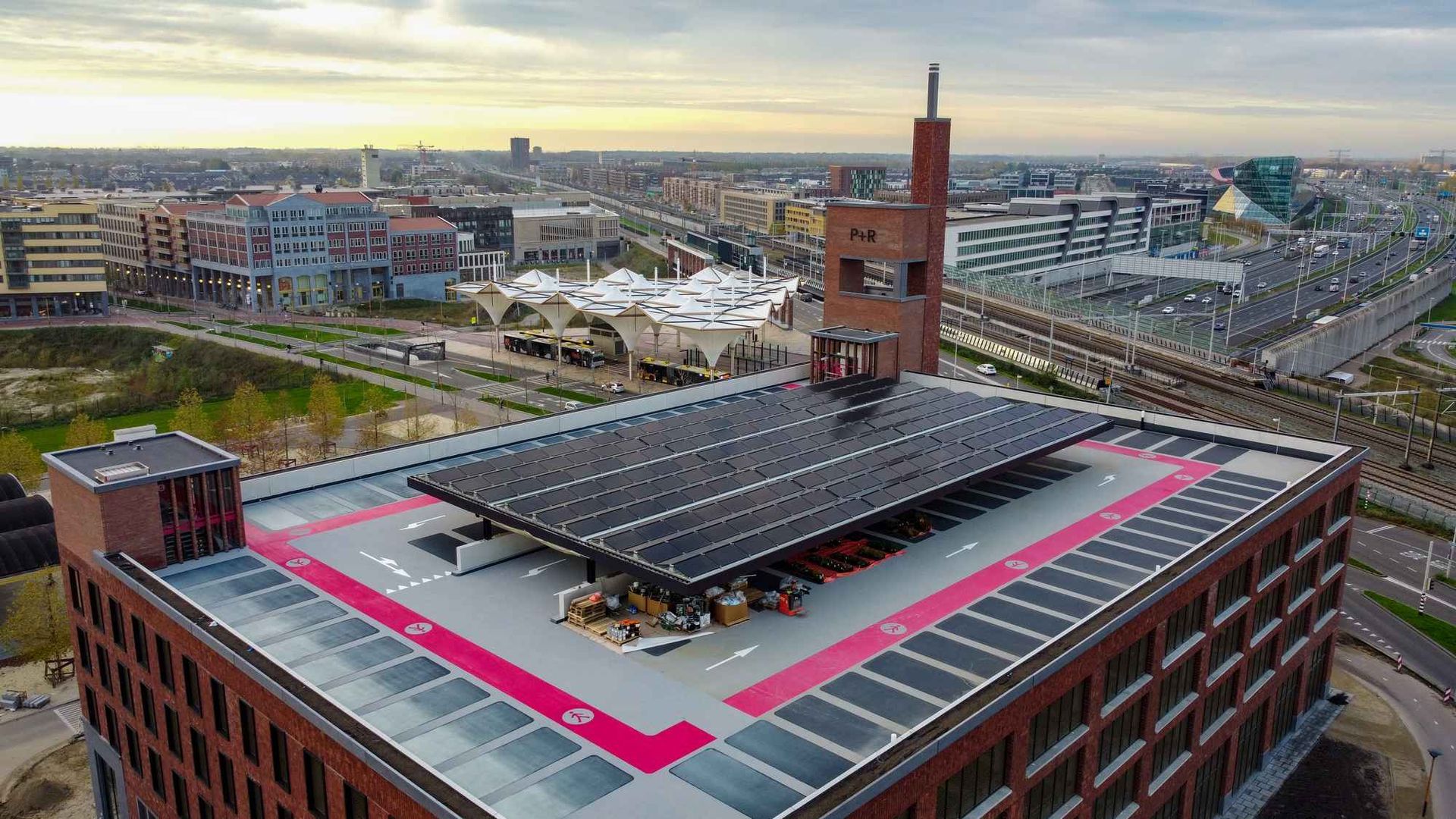 Een luchtfoto van een groot gebouw met veel zonnepanelen op het dak.