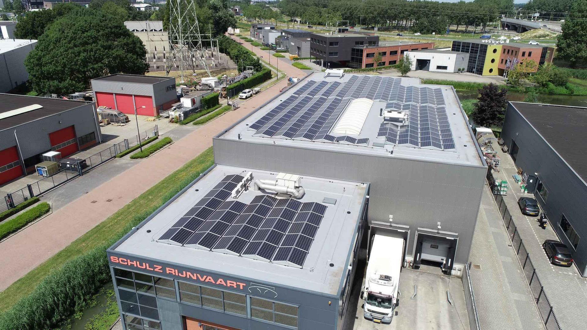 Een luchtfoto van een magazijn met zonnepanelen op het dak.