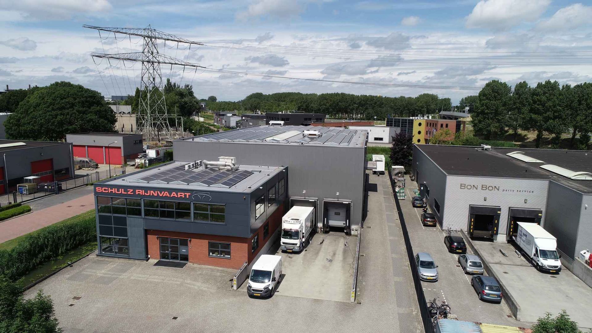 Een luchtfoto van een pakhuis met ervoor geparkeerde vrachtwagens.