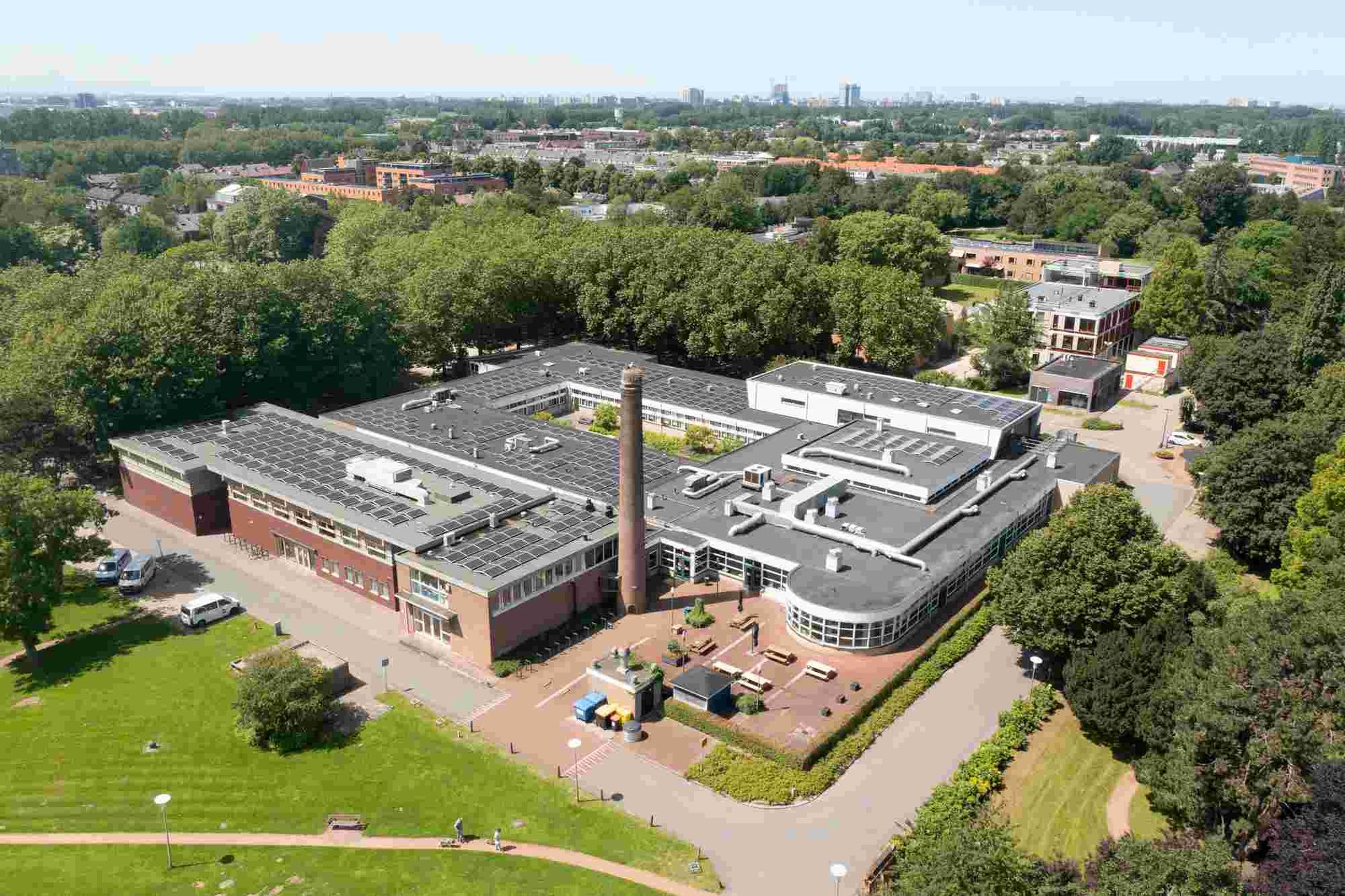 Een luchtfoto van een groot gebouw omgeven door bomen en gras.