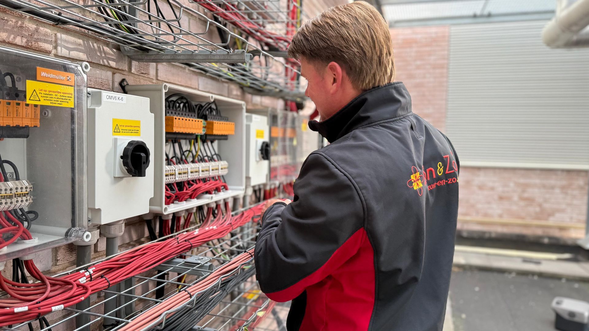Een man werkt aan een elektrisch paneel in een kas.