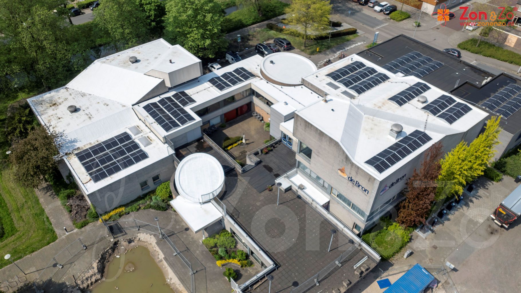 Een luchtfoto van een groot gebouw met zonnepanelen op het dak.