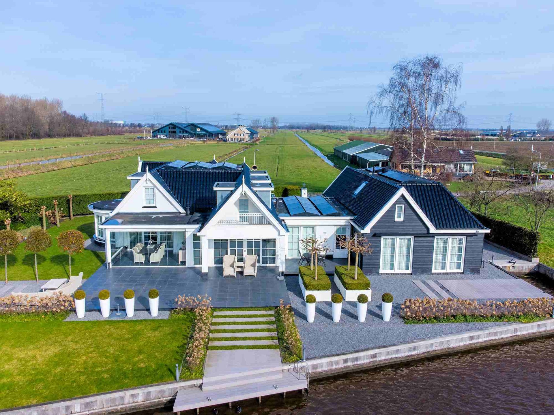 Een luchtfoto van een groot huis naast een waterpartij.