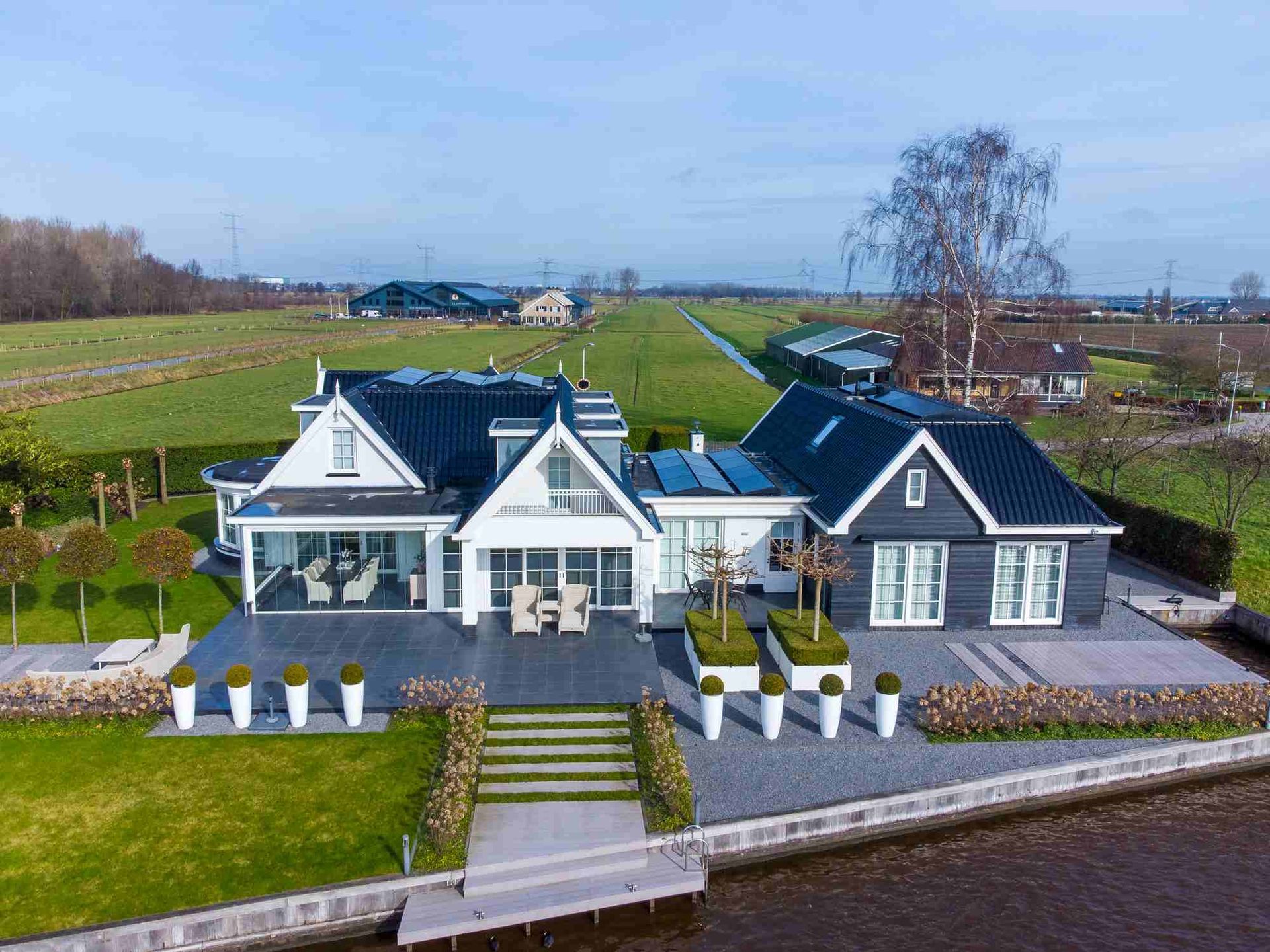 Een luchtfoto van een groot huis naast een waterpartij.