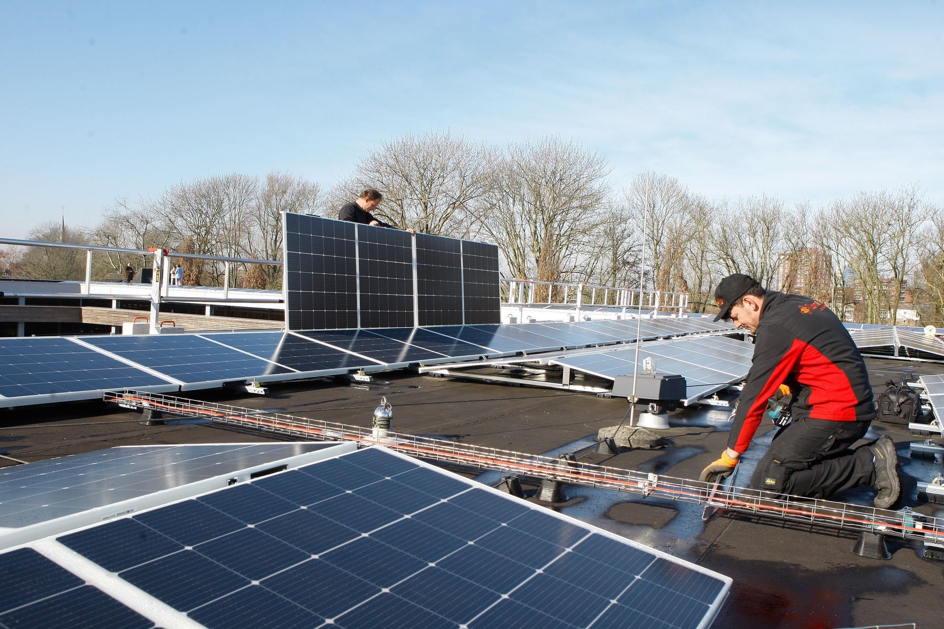 Een man installeert zonnepanelen op het dak van een gebouw.