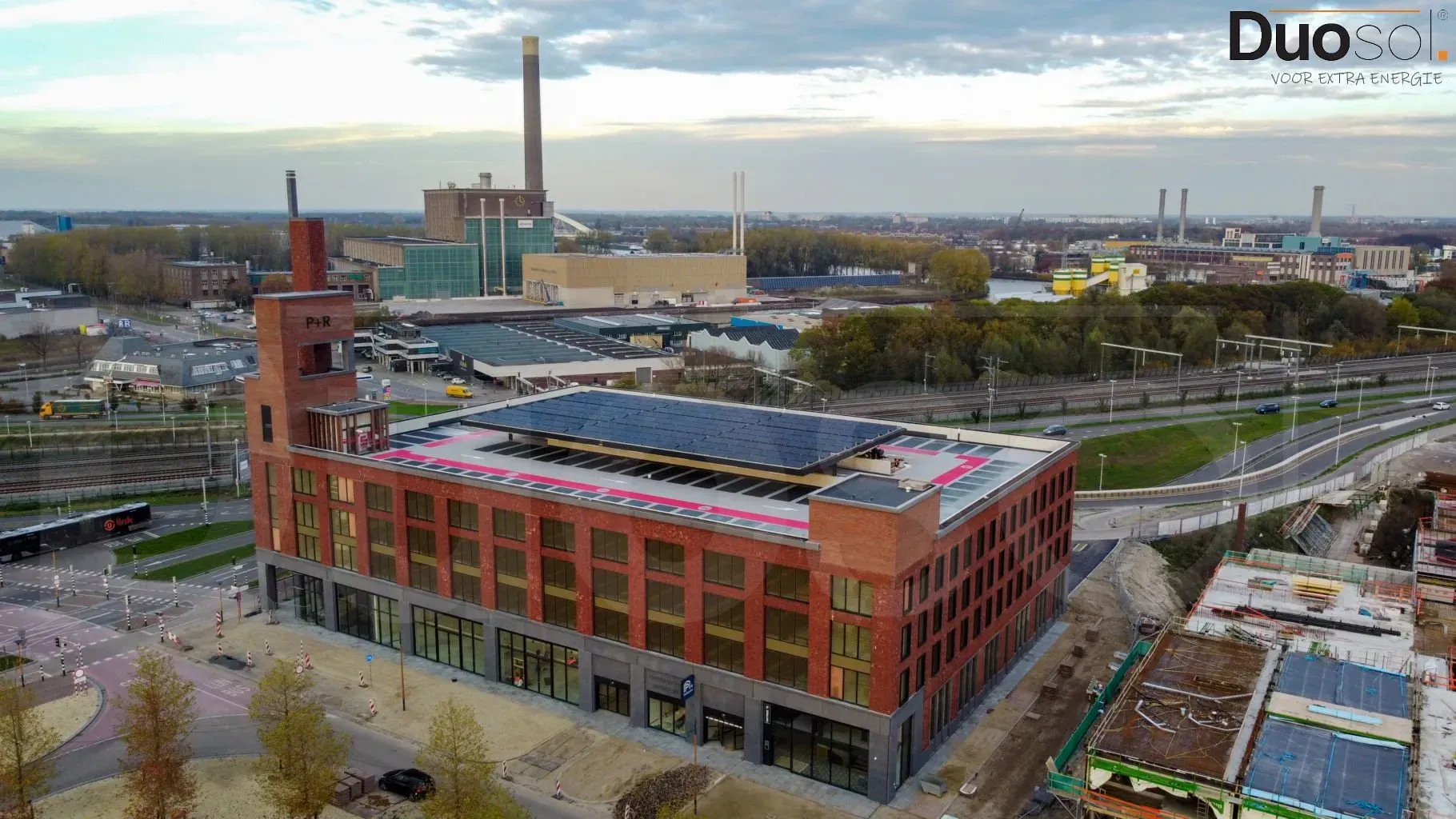 Een luchtfoto van een groot bakstenen gebouw met zonnepanelen op het dak.