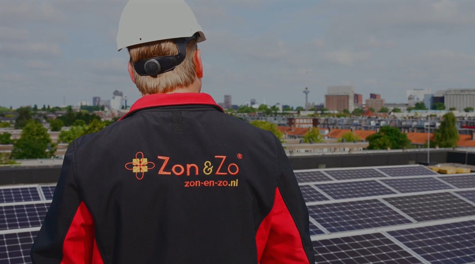 Een man staat op een dak met zonnepanelen.