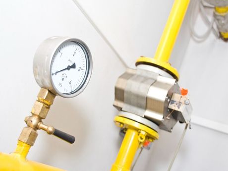 A pressure gauge is sitting on top of a yellow pipe.