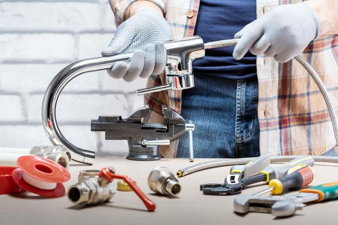 A man is fixing a faucet with tools on a table.