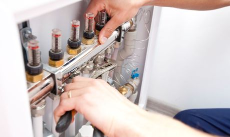 A person is fixing a pipe with a wrench.