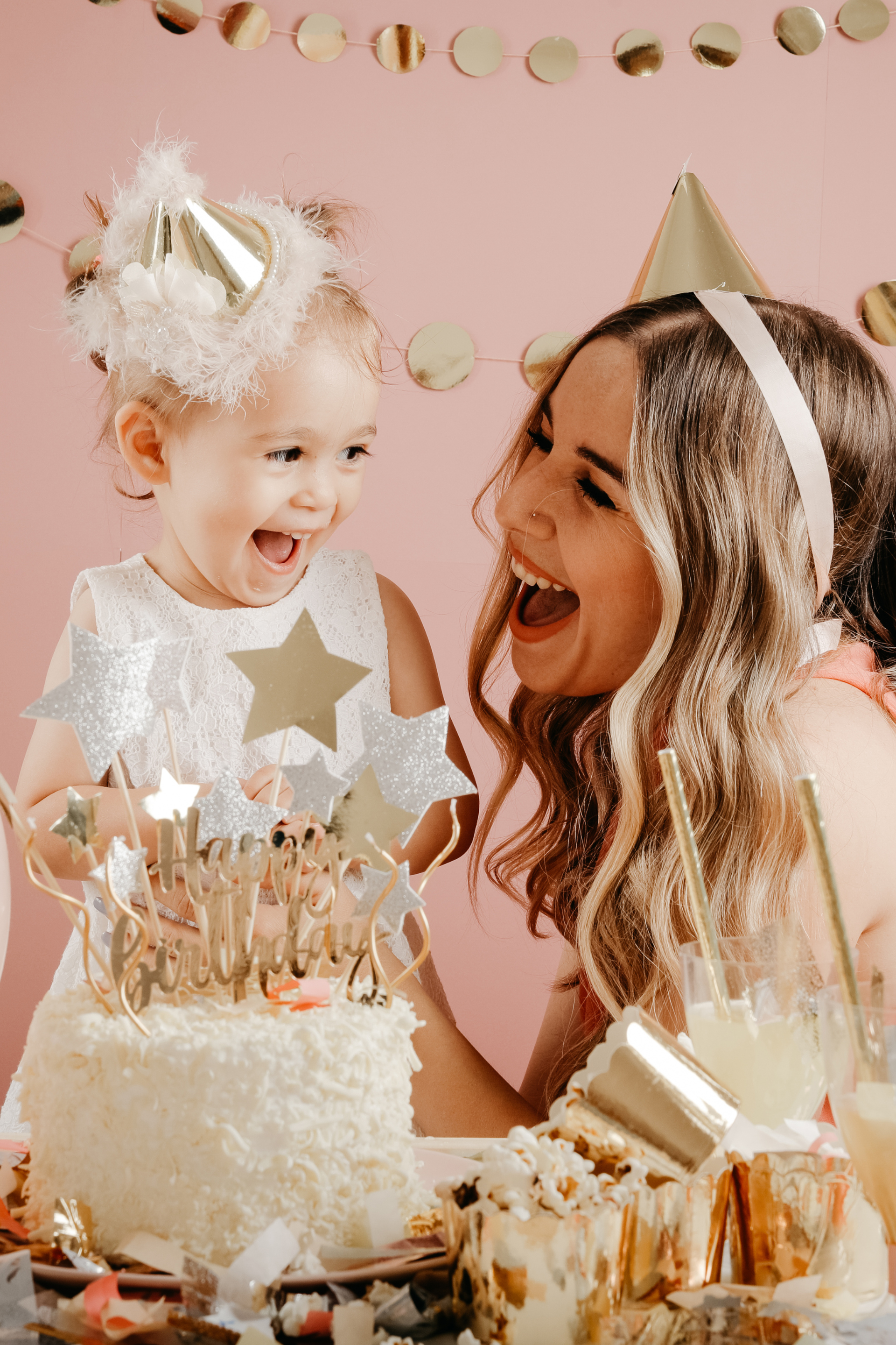 A woman and a little girl are sitting at a table with a birthday cake.
