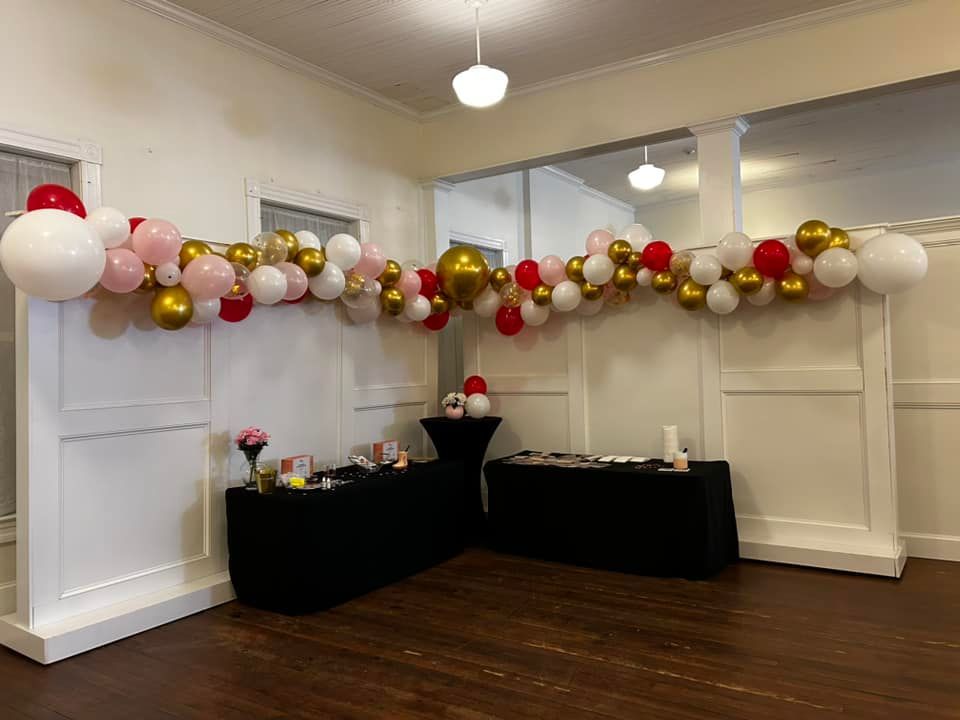 A room with balloons hanging from the ceiling and tables.