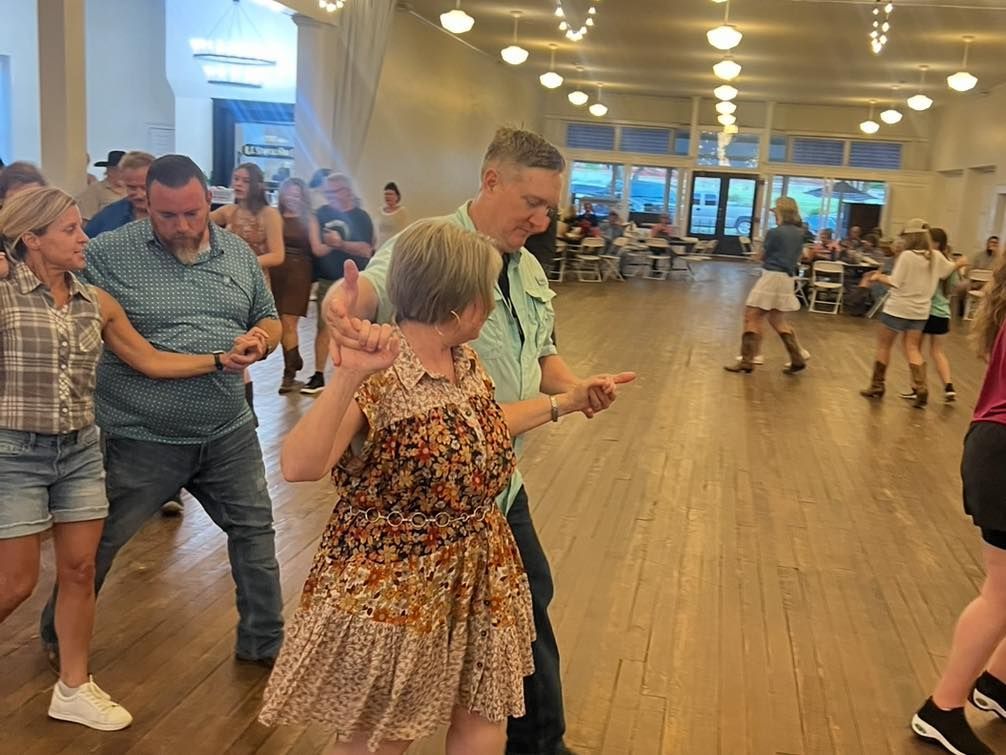 A group of people are dancing in a large room.