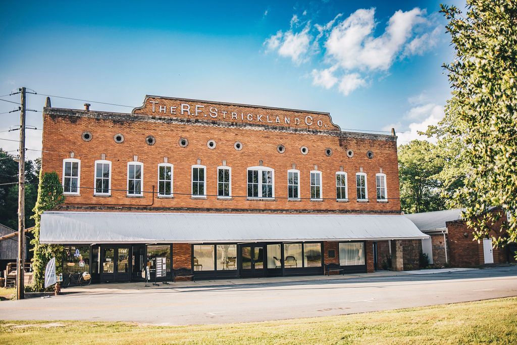 A large brick building with a lot of windows is sitting in the middle of a field.