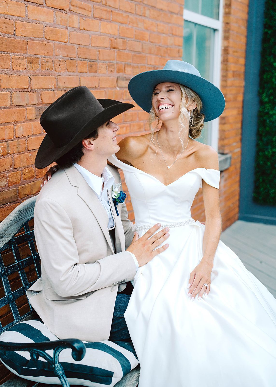A bride and groom are kissing in front of a wall.