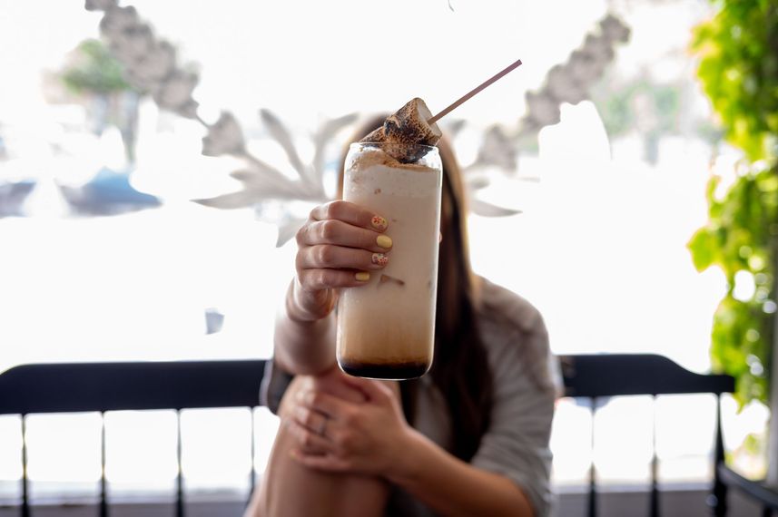 A woman is holding a milkshake in front of her face.