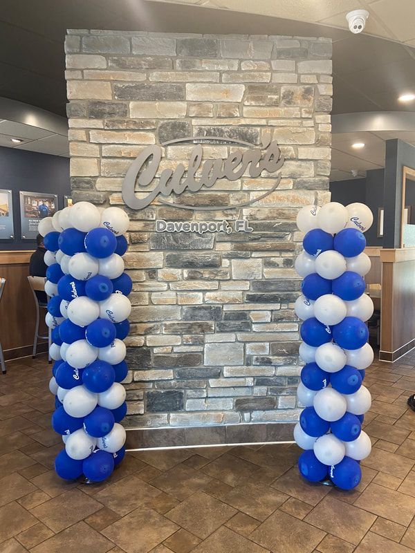 A brick wall with blue and white balloons in front of it