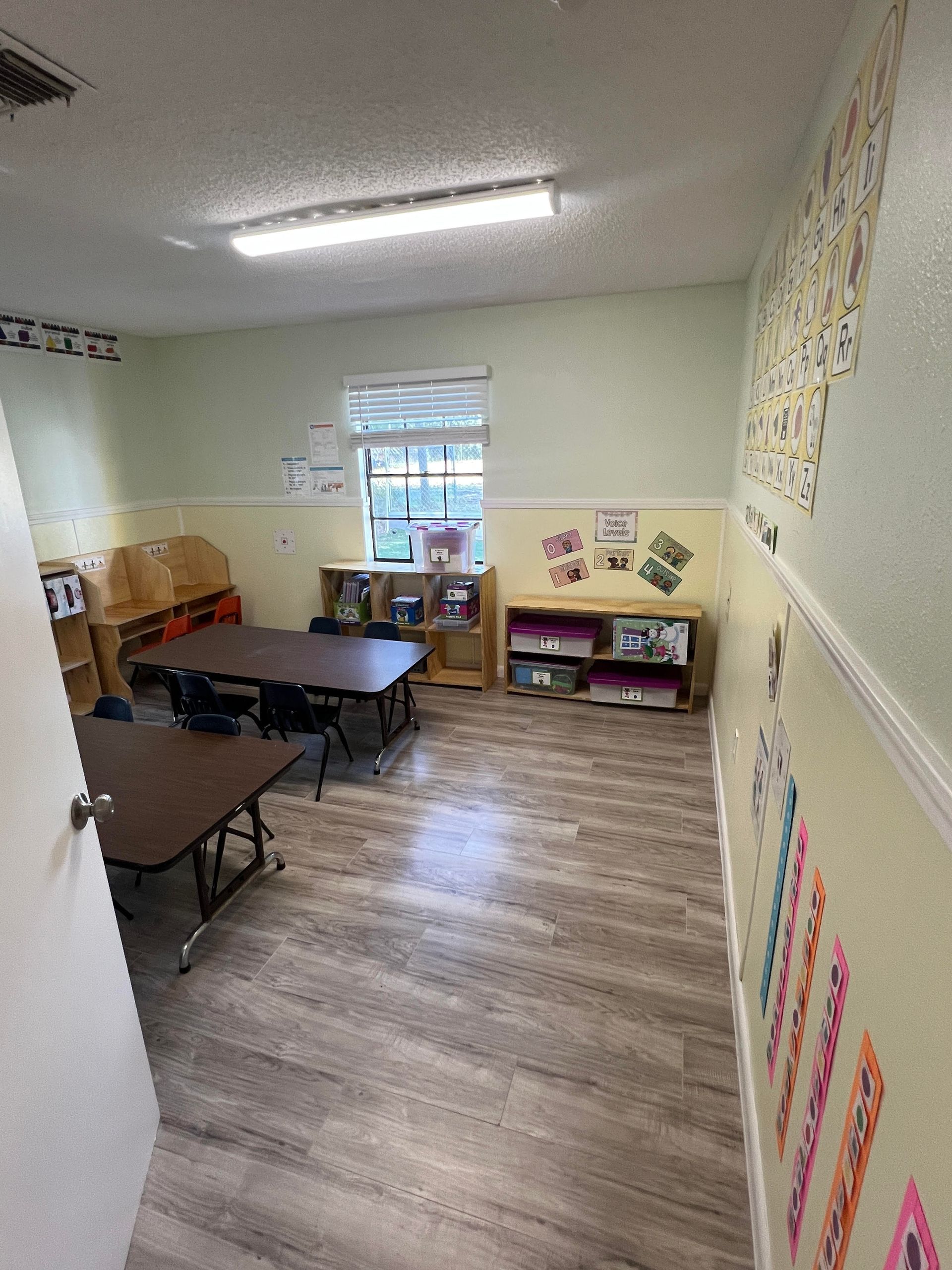 A classroom with tables and chairs and a window.