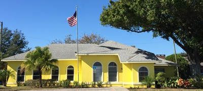 A yellow house with an american flag flying in front of it.