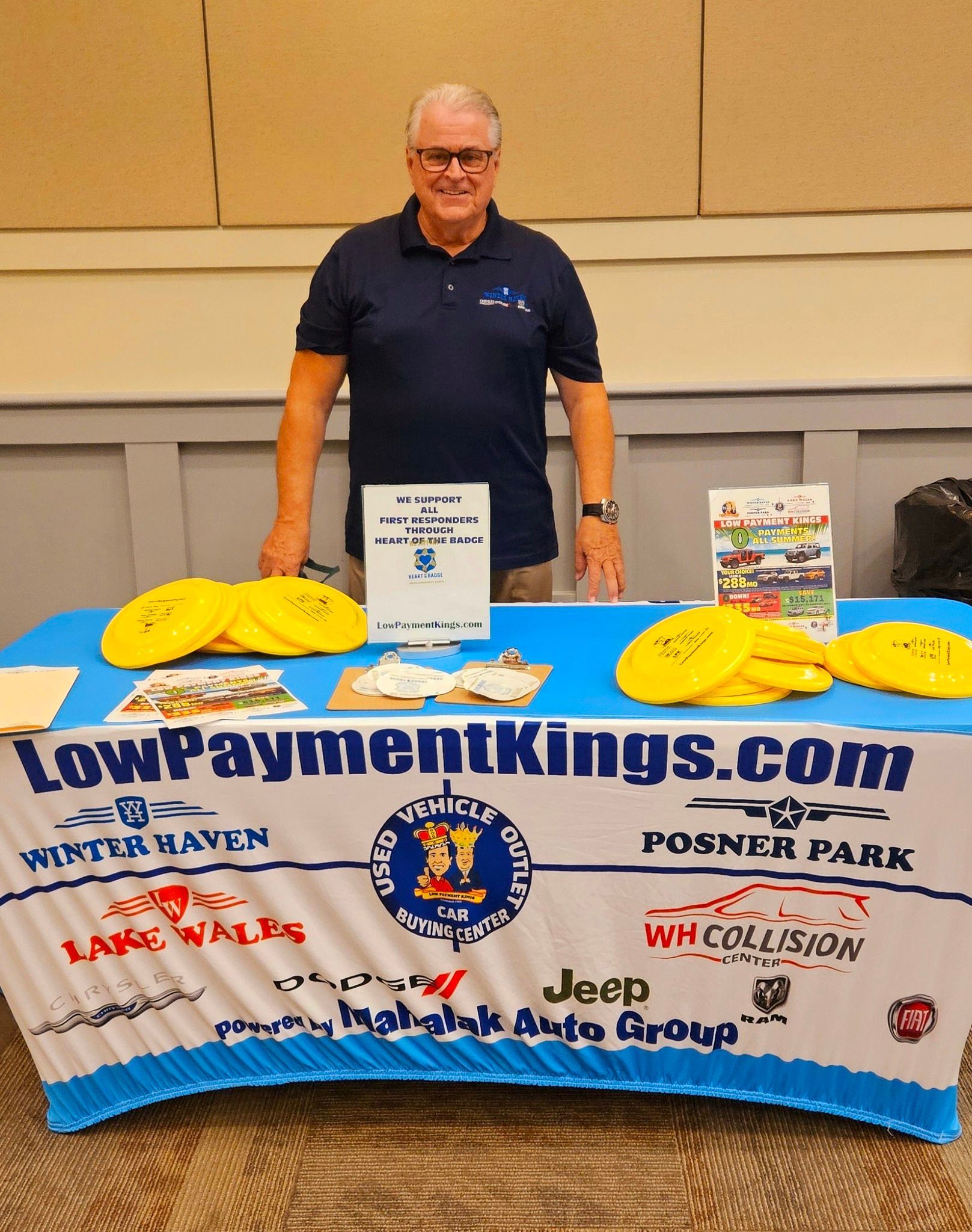 A man stands in front of a table that says lowpaymentkings.com