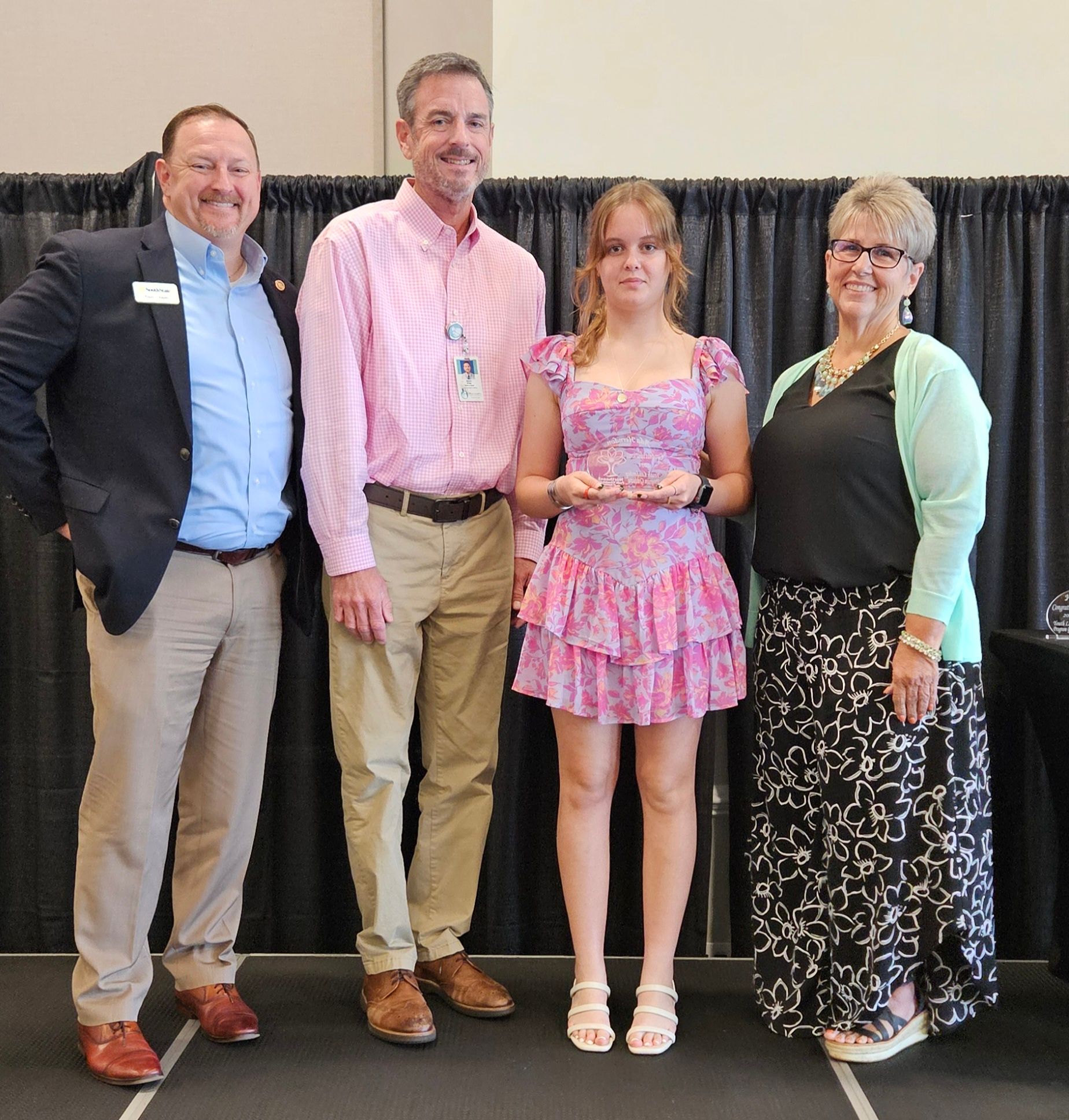 A group of people standing next to each other including a woman in a pink dress