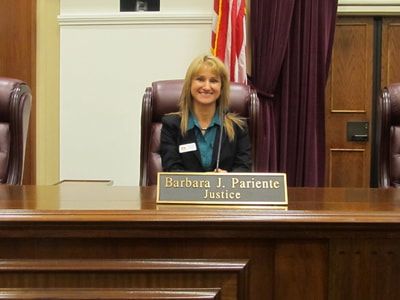 A woman is sitting at a desk with a name plate that says barbara j. pariente justice