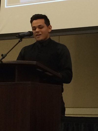 A man stands at a podium speaking into a microphone