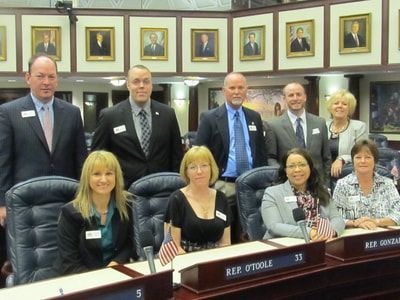 A group of people sitting at a table with a name plate that says ref othole