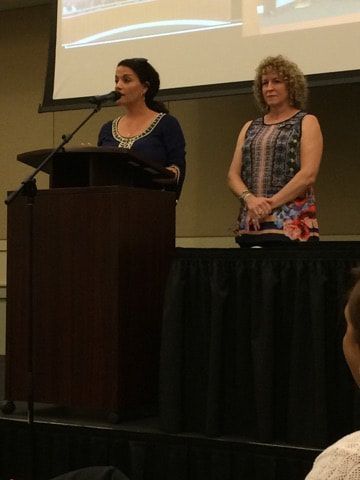 Two women are standing at a podium giving a presentation