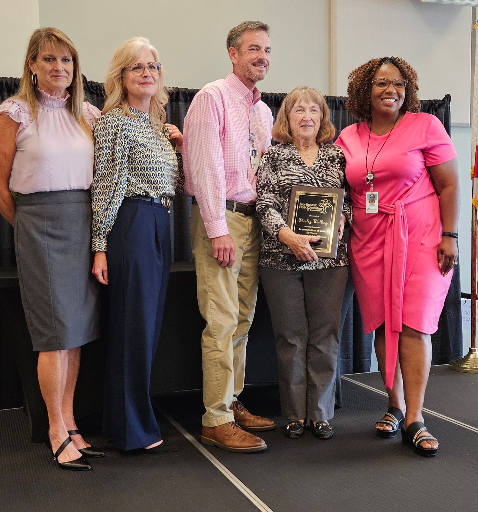 A group of people posing for a picture with one woman in a pink dress