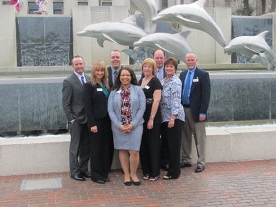 A group of people standing in front of a statue of dolphins