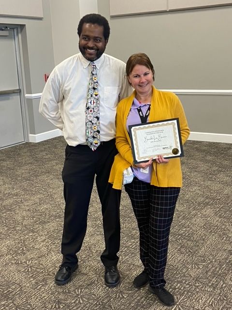 A man and a woman are standing next to each other holding a certificate.