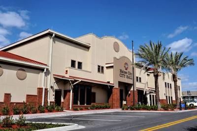 A large building with a red roof and palm trees in front of it.