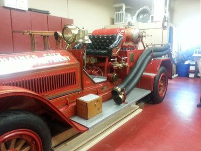 An old red fire truck is parked in a garage.