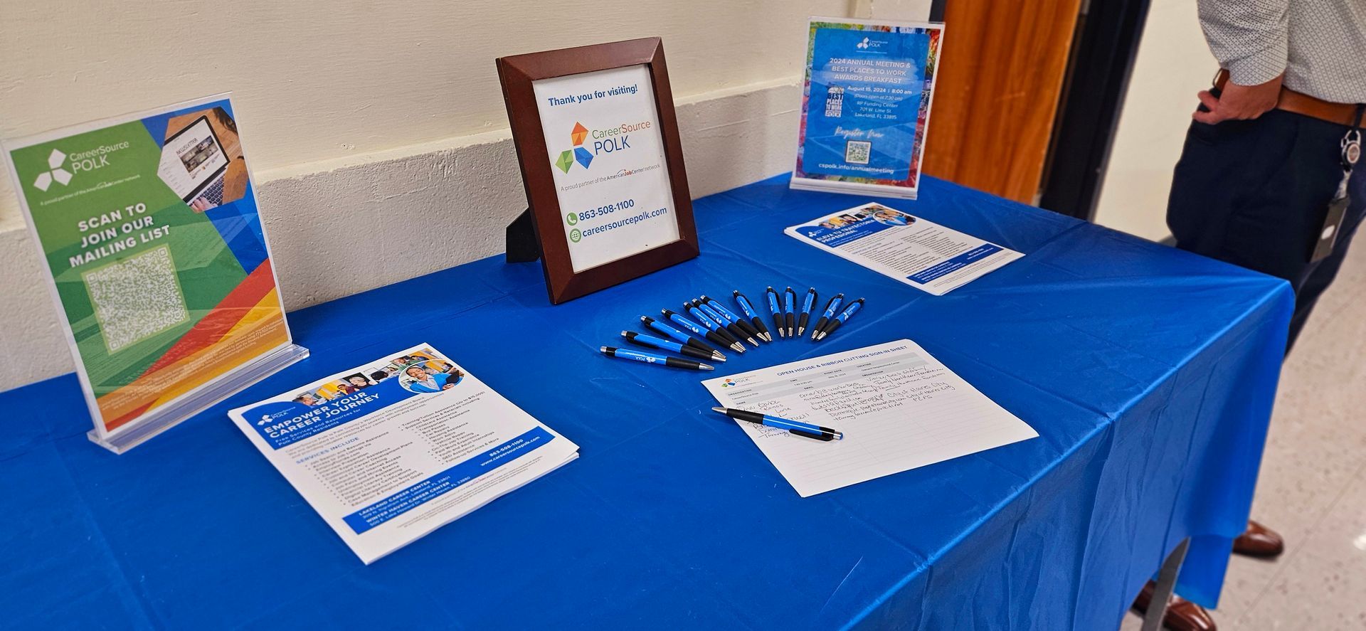 A blue table with papers , pens , and a picture on it.