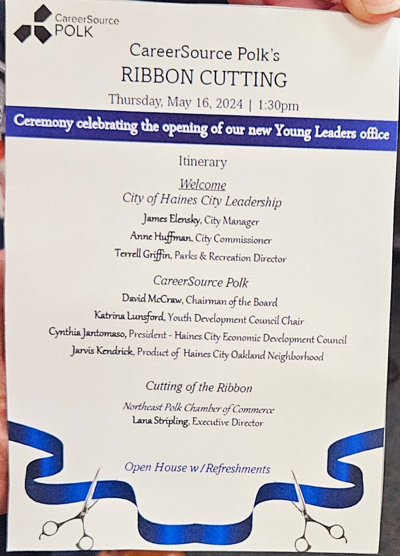 A person is holding a pamphlet for a ribbon cutting ceremony