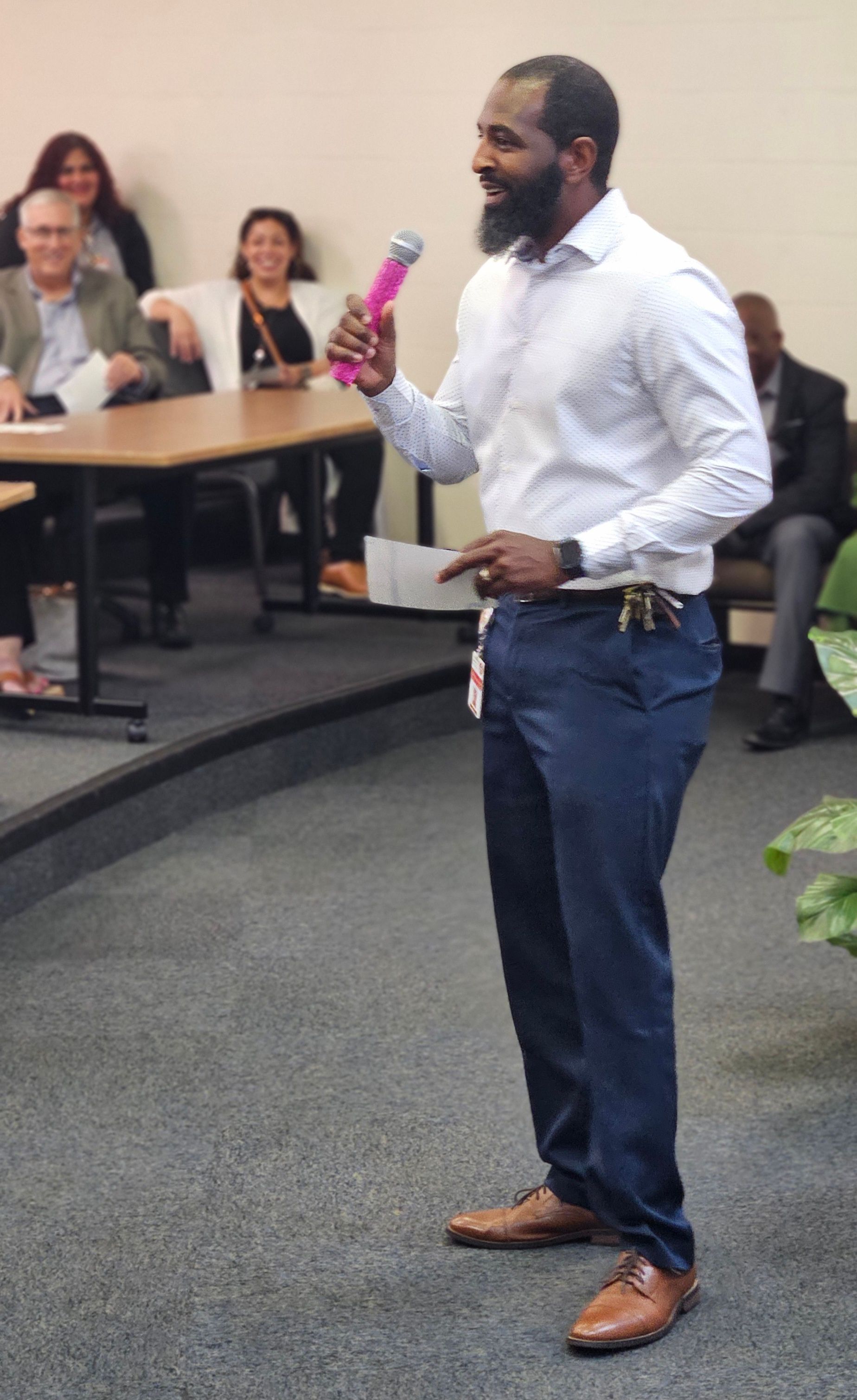 A man is holding a pink microphone in front of a group of people