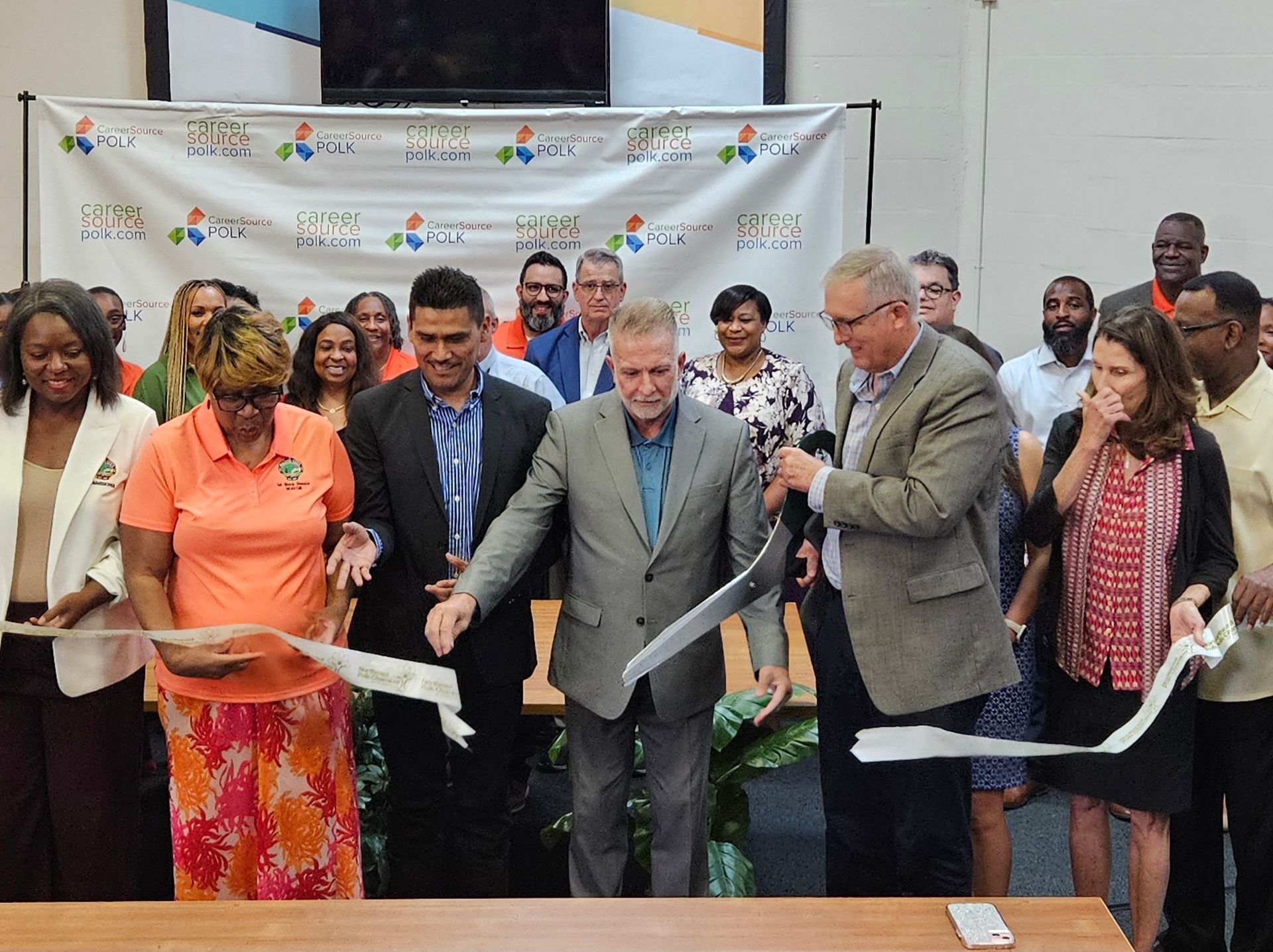 A group of people are cutting a ribbon in a room.