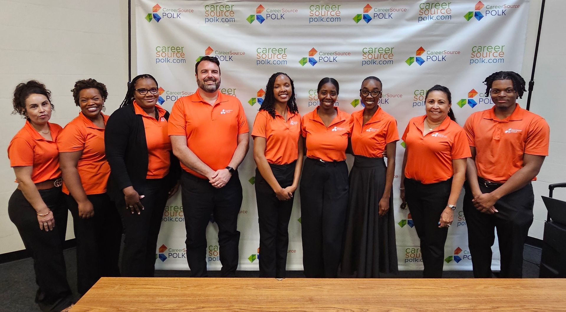 A group of people in orange shirts are posing for a picture.