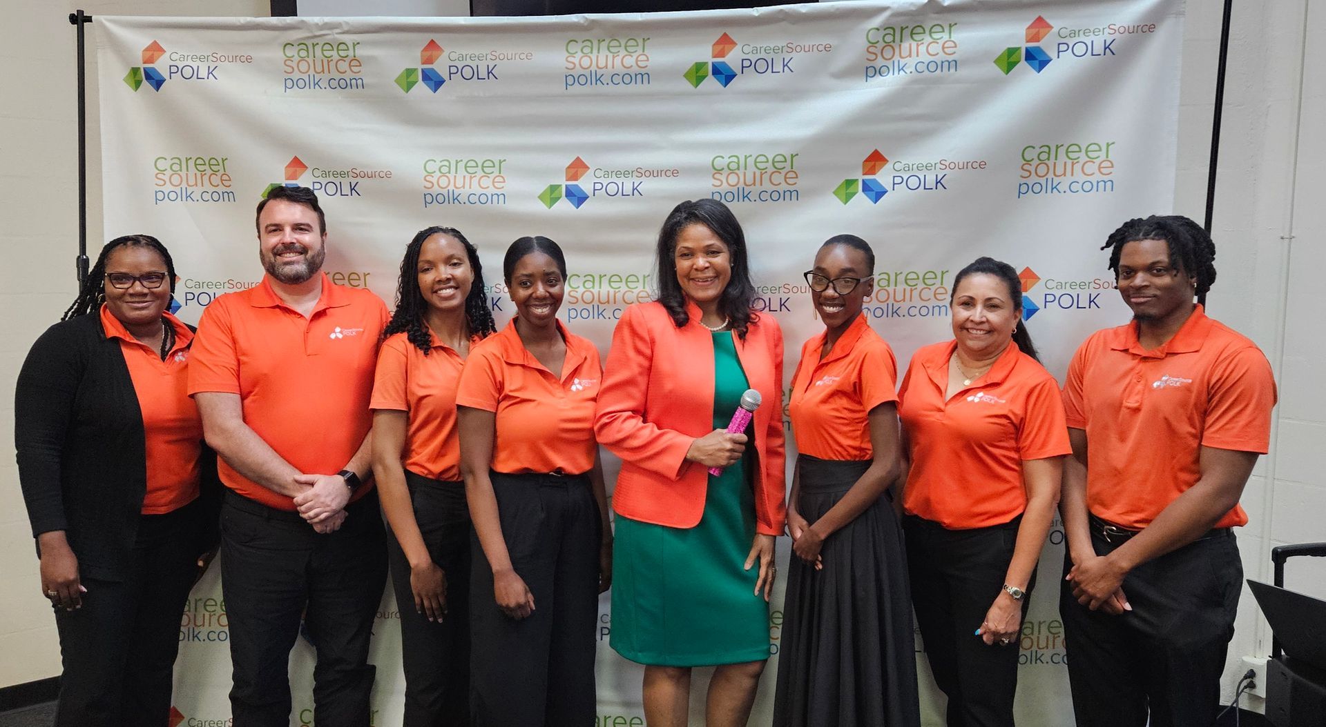 A group of people in orange shirts are posing for a picture.