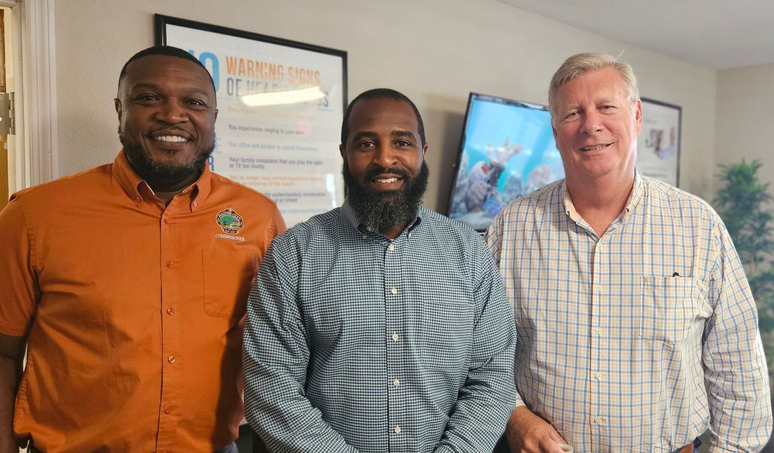 Three men are posing for a picture together in a room.