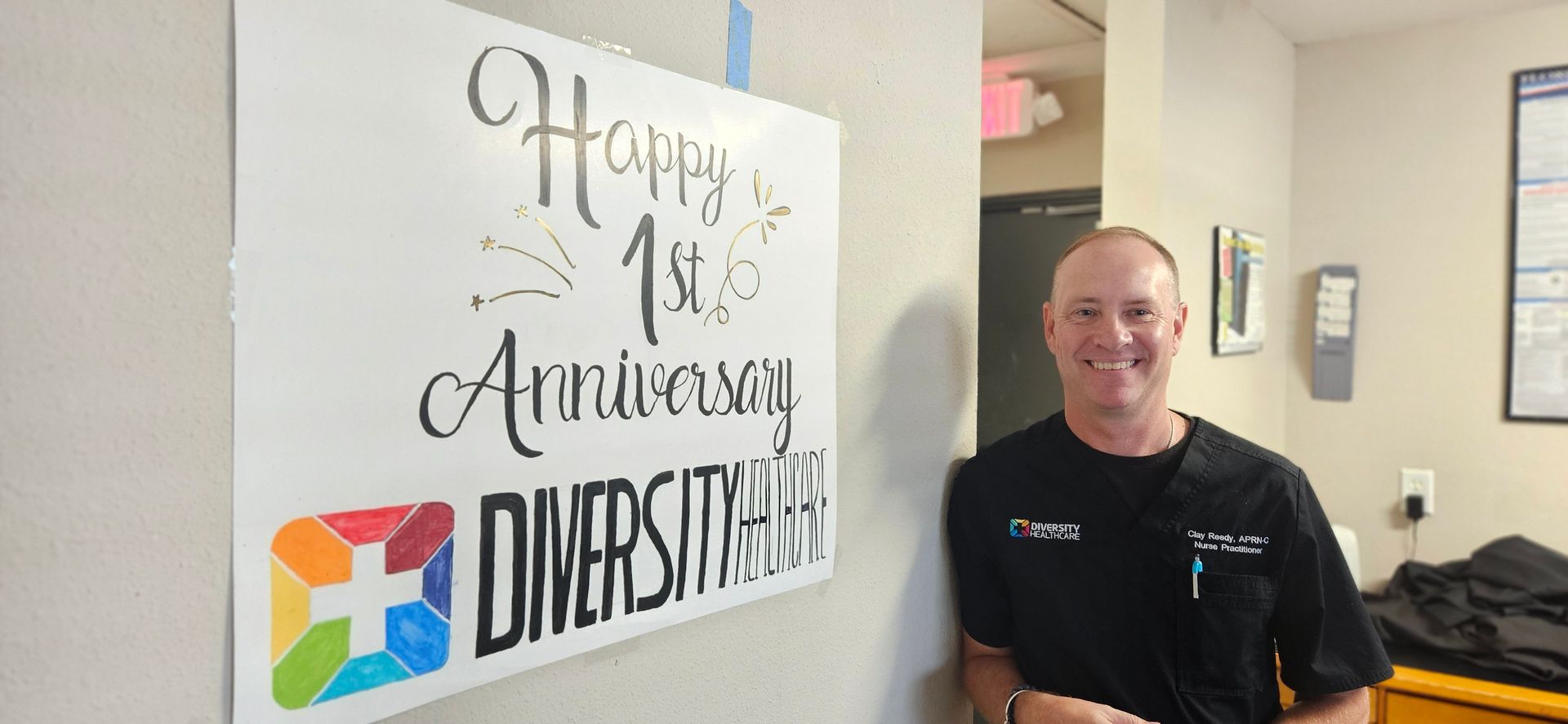 A man is standing in front of a sign that says happy 1st anniversary diversity