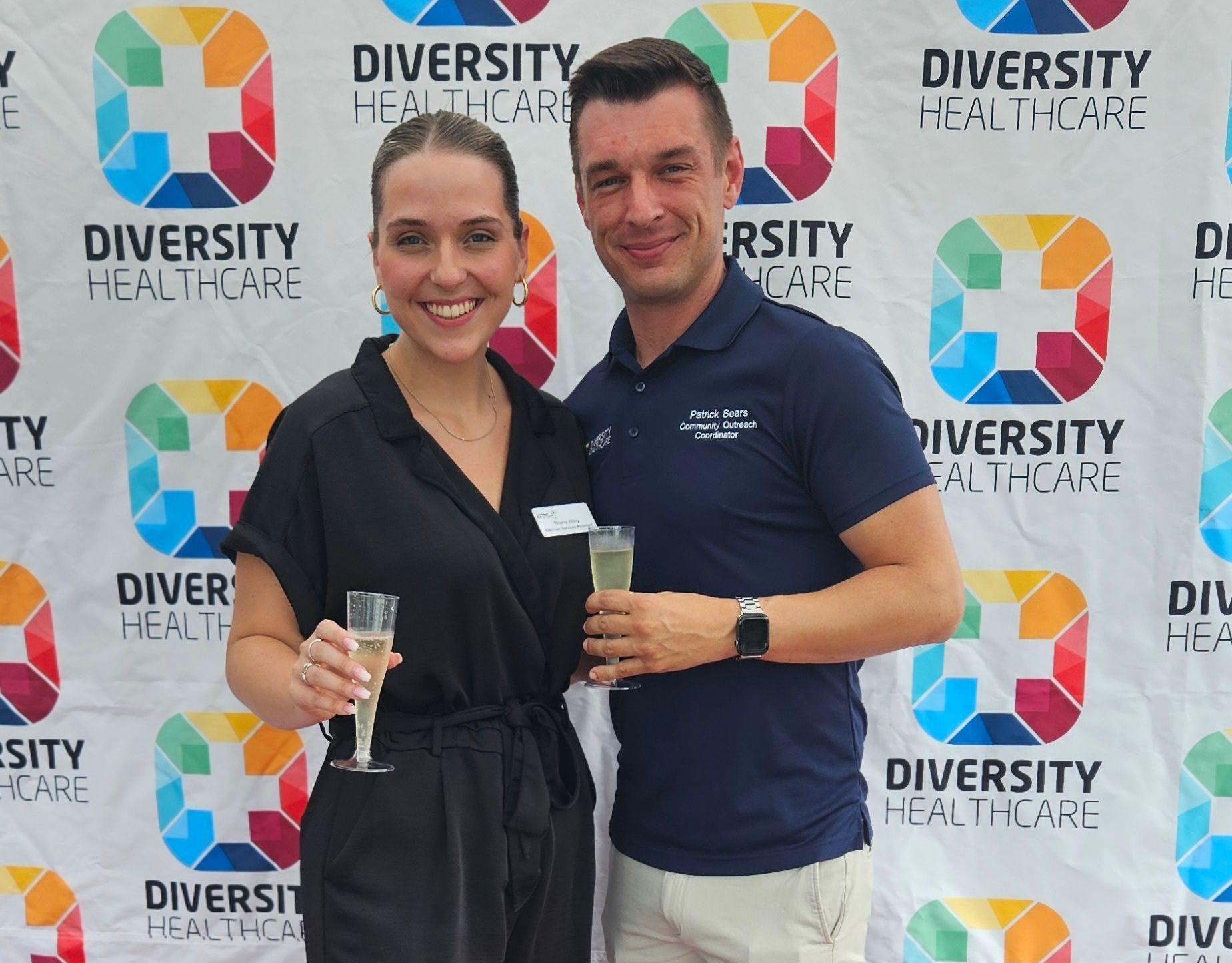 A man and a woman are posing for a picture in front of a diversity healthcare backdrop.