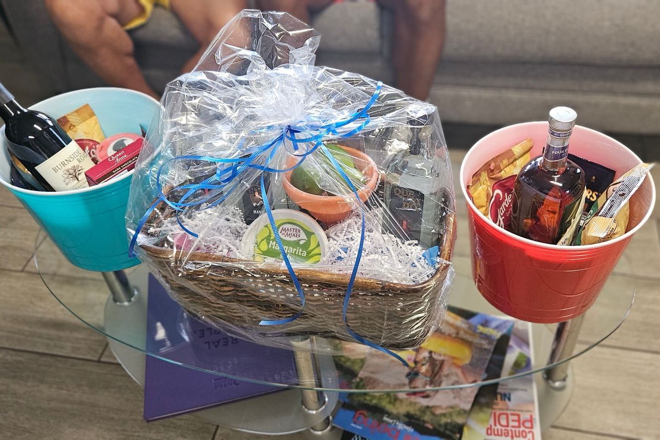 A person is sitting on a couch next to a table with buckets of food and wine.