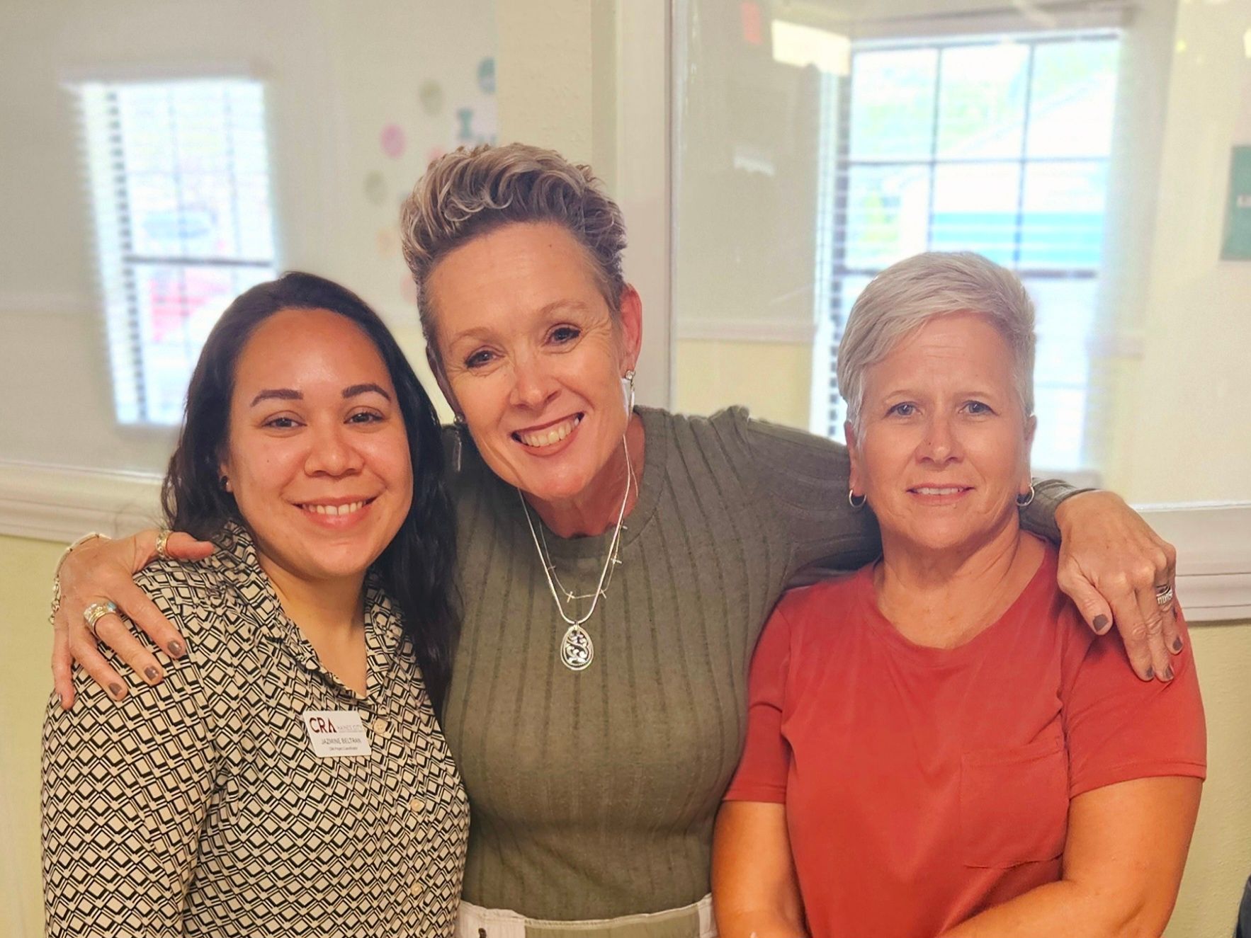 Three women are posing for a picture together in a room.