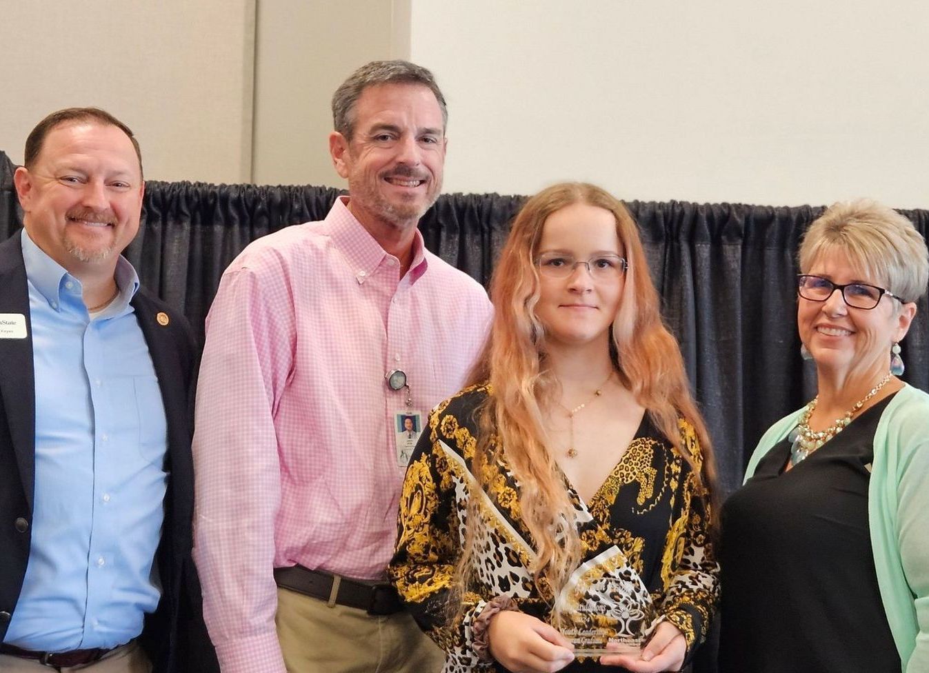 A group of people are posing for a picture with a woman holding a trophy.