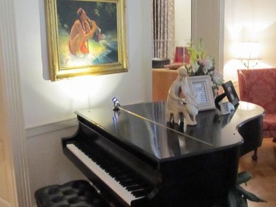A piano in a living room with a painting on the wall above it